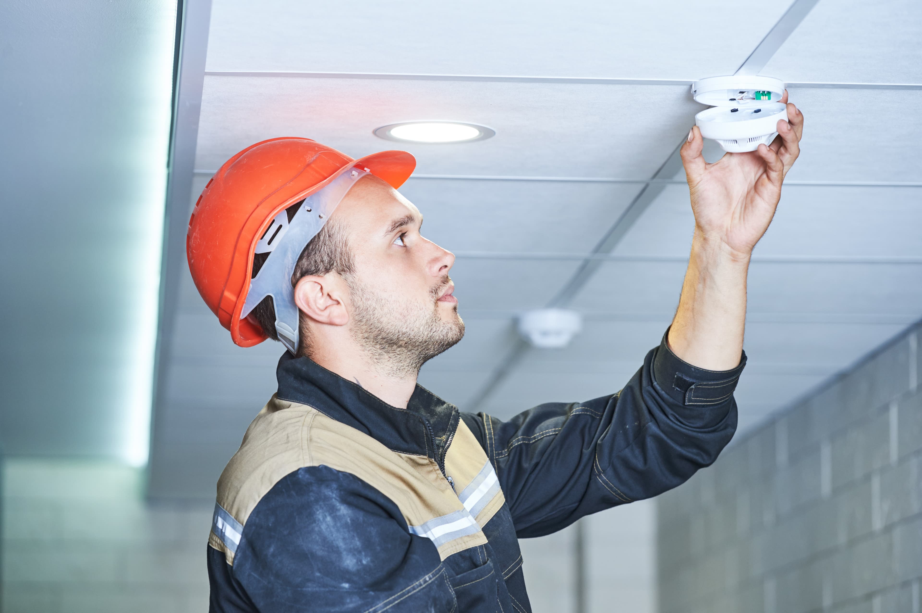 person changing a fire alarm